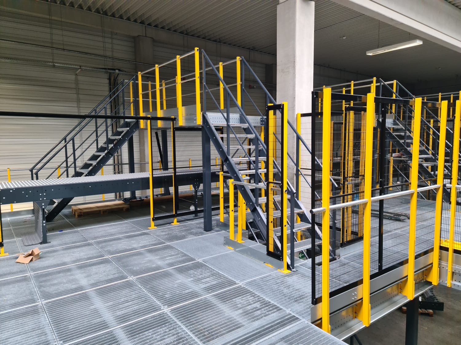 Mezzanine vloer op maat met stalen constructie, trap en gele leuningen in magazijn