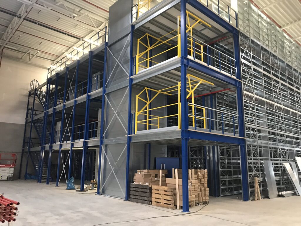 Mezzanine vloer met stalen constructie, trappen en gele leuningen op maat voor magazijn