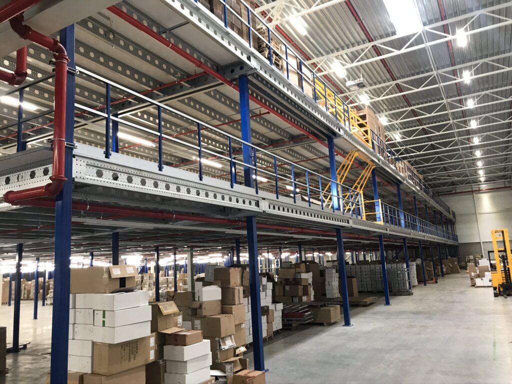 Mezzanine vloer op maat in magazijn met stalen constructie, blauwe kolommen en gele trap