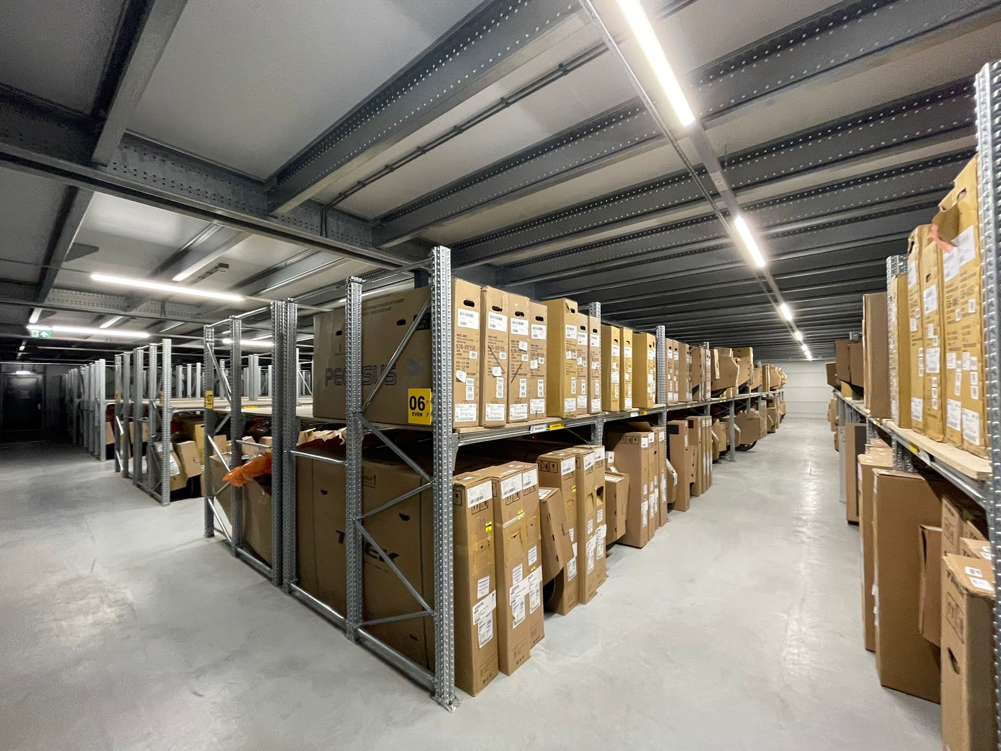 Entresolvloer op maat met stalen constructie, vloerplaten en opslagrekken vol dozen in loods